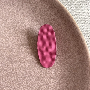 Pink oval hair clip with hammer texture on a decorative tray for girls