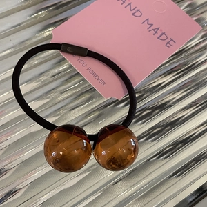 Primer plano de goma de pelo elástica con cuentas de ámbar en tarjeta de regalo rosa