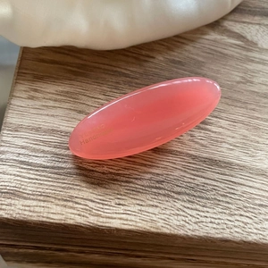 Detail of pink oval resin hair clip with Handmade text on smooth acetate surface