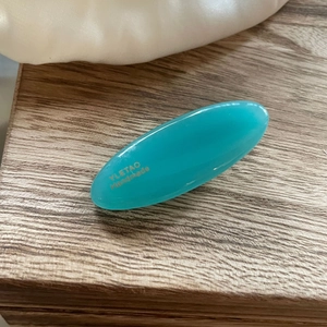 Detail of green oval resin hair clip with gold YLETAO Handmade lettering on wood
