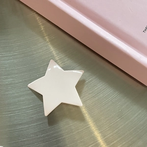 Minimalist pink star hair clip with glossy enamel finish on a sleek metallic surface