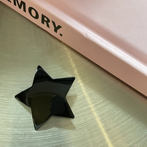 Close-up of a glossy black star hair clip placed on a sleek brushed metal surface