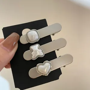 Detailed view of three pearl-textured hair clips in square, bear, and heart shapes