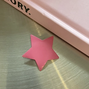 Pink star-shaped alloy hair clip on a metal surface with a minimalist aesthetic style
