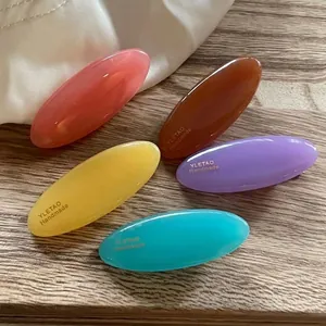 Set of minimalist colorful oval resin hair clips in pastel tones on a silk background