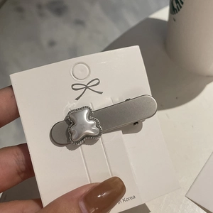 Minimalist silver metal hair clip with a resin bear and rhinestones on a white card