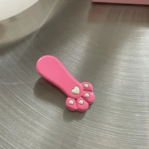 Süße rosa Katzenpfoten-Haarklammer mit weißen Herzdetails auf Metallhintergrund