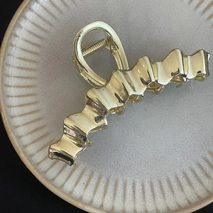 Elegant gold metal wave hair claw clip with glossy finish for a minimalist style