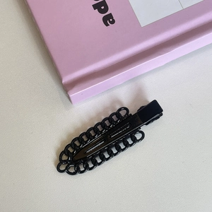 Detail of minimalist black metal duckbill hair clip with stylish hollow chain pattern