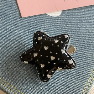Gros plan d'une pince à cheveux étoile noire avec paillettes argentées sur denim