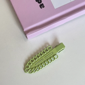 Detail shot of a matte mint green metal hair clip with hollow chain decorative edges