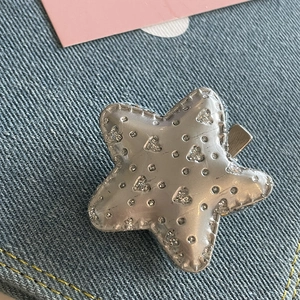 Détail macro de la pince étoile Y2K avec cœur pailleté argenté sur tissu denim bleu