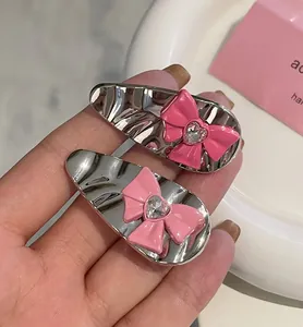 Détail de barrettes argentées avec nœuds roses et pierres de zircon en cœur