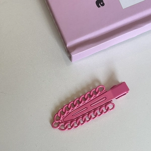 Detail of rose pink metal chain duckbill hair clip on a decorative book background