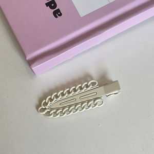 Detailed view of the creamy white chain-link metal duckbill clip with retro texture