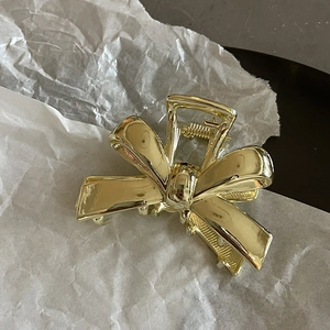 Elegant gold metal bow hair claw clip for women with a minimalist polished mirror finish