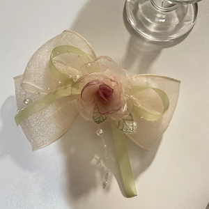 Detailed close-up of champagne organza bow hair clip with silk rose and faux pearls