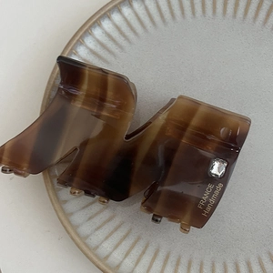 Dettaglio molletta per capelli tartarugata con cristallo e scritta dorata fatta a mano