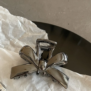 Sleek metal bow hair claw clip with mirror finish for elegant half-up hairstyles