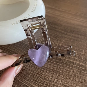 Pince à cheveux marron avec cœur violet et pois sur fond de table en bois