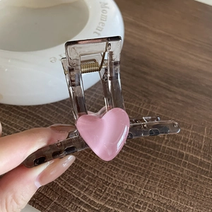 Pince à cheveux en résine marron avec cœur rose et ressort métallique en main
