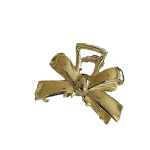 Elegant gold bow-shaped metal hair claw clip with a polished finish on white background