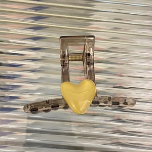 Détail d'une pince à cheveux marron translucide avec cœur jaune et mécanisme à ressort métal