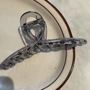 Gros plan sur la pince à cheveux de 14 cm en acrylique gris fumé avec son ressort en métal