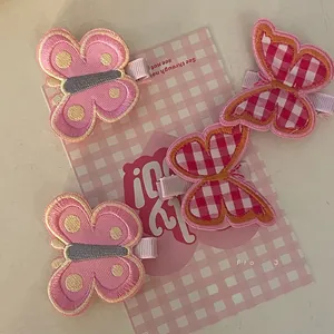Detail of cute embroidered butterfly hair clips with pink and red checkered patterns