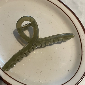 Vue détaillée de la grande pince à cheveux vert olive avec ressort doré sur une assiette
