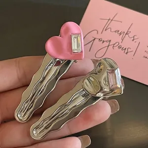 Fermagli per capelli a cuore rosa e argento con cristalli, mostrati con uno sfondo caldo