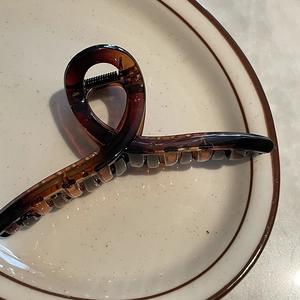 Détail d'une grande pince à cheveux ambre de 14 cm en résine sur un plateau blanc