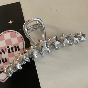 Dettaglio della molletta per capelli Y2K in metallo argento con design a più stelle