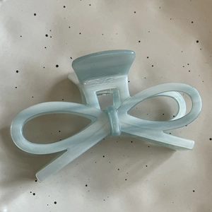 Detail view of light blue acetate bow hair claw clip with elegant marble texture