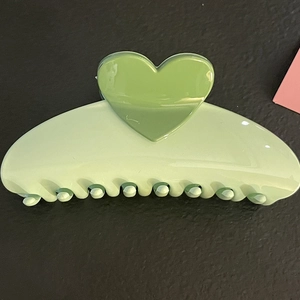Detail view of the green heart-shaped hair claw clip with smooth acrylic finish