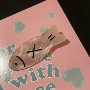 Cute pearlescent pink fish hair clip with fishbone design on a decorative card