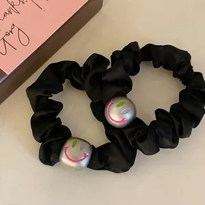 Close-up of black satin hair scrunchies with cute smiling face metallic beads charms