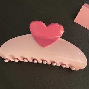 Detail showing the pink heart ornament and smooth resin finish of the shark hair claw