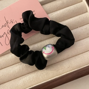 Elegant black satin scrunchie with silver smiley cube bead on velvet display tray