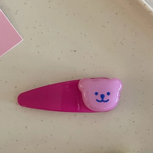 Gros plan sur une pince à cheveux en acrylique rose avec breloque ours mignon