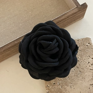 Detailopname van de elegante zwarte stoffen rozen haarklem met verfijnde blaadjes