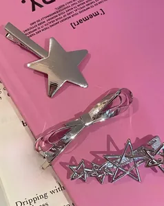 Vue macro de barrettes étoile Y2K argentées et clips nœud sur fond rose vif