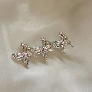 Détail d'une barrette papillon avec pierres roses et strass argentés sur du satin