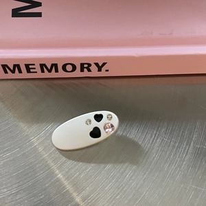 Detail of matte silver hair clip with hollow hearts and pink rhinestones on metal surface