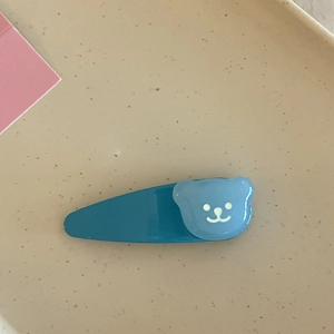 Gros plan d'une barrette ours bleue mate pour filles sur un plateau en céramique
