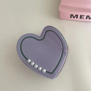 Close-up of a purple heart-shaped shark hair clip with elegant white pearl embellishments
