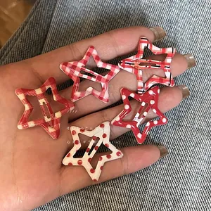 Detail of five Y2K star hair clips featuring red and white plaid and polka dot patterns