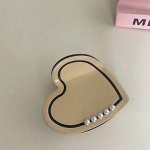 Close-up of beige heart hair claw with black trim and five elegant white pearl accents