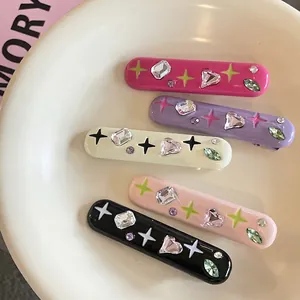 Set of five colorful rhinestone hair clips with star patterns in a ceramic bowl