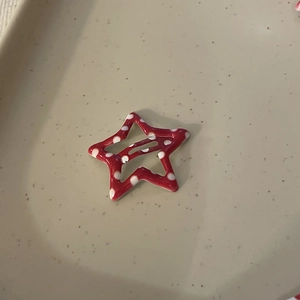 Red Y2K star hair clip with white polka dots on a beige ceramic display plate